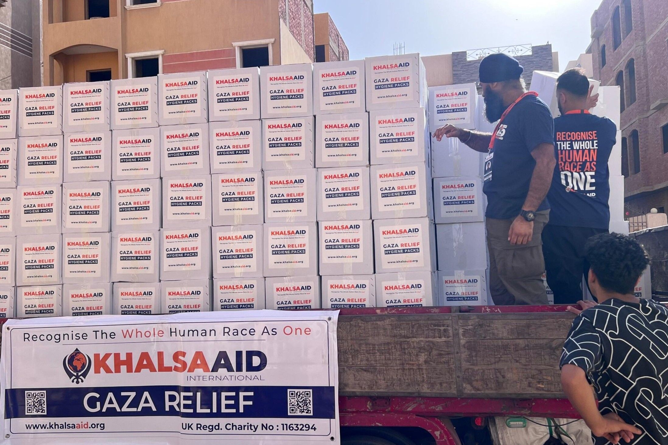 Khalsa Aid coordinators packing a convoy of trucks with Gaza Relief packs.