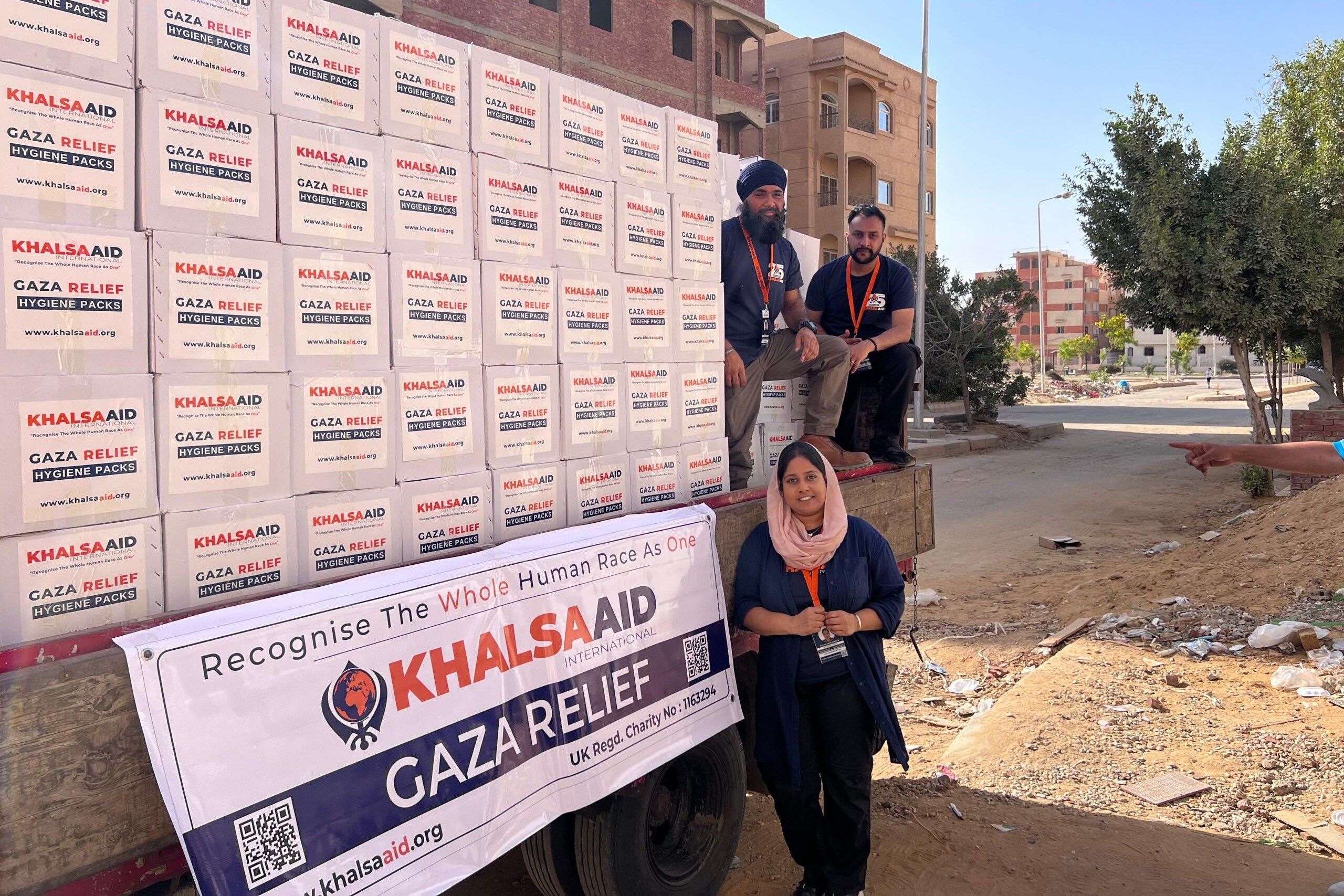 Khalsa Aid coordinators packing a convoy of trucks with Gaza Relief packs.