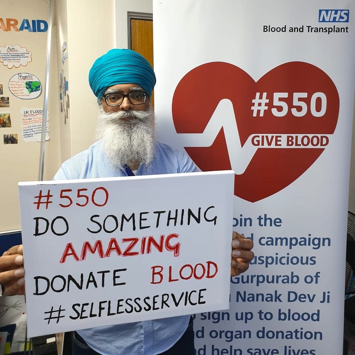 CEO Ravi Singh holding a sign that reads: '#550 DO SOMETHING AMAZING. DONATE BLOOD. #SELFLESSSERVICE'