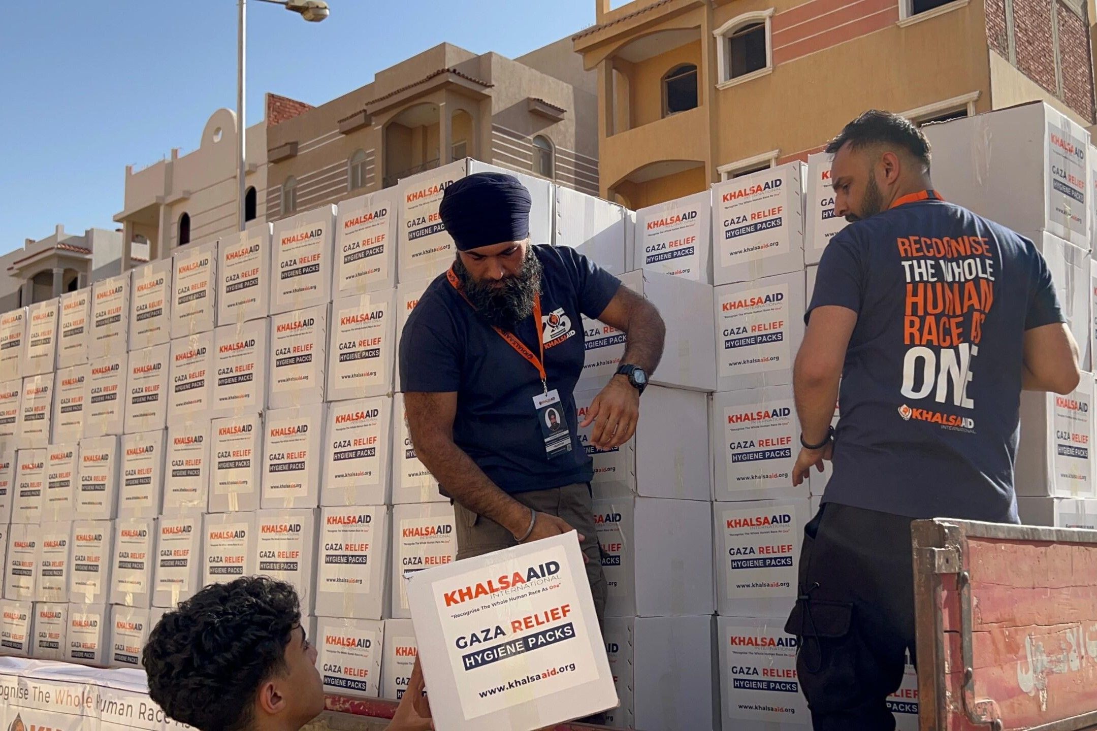 Khalsa Aid coordinators packing a convoy of trucks with Gaza Relief packs. 